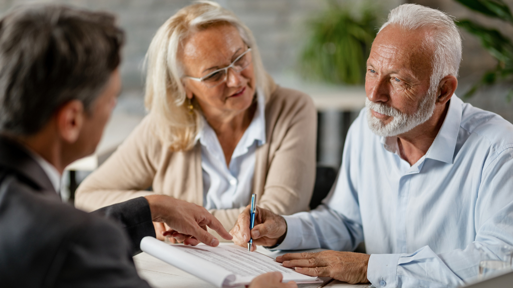 Elderly couple signing papers with a solicitor